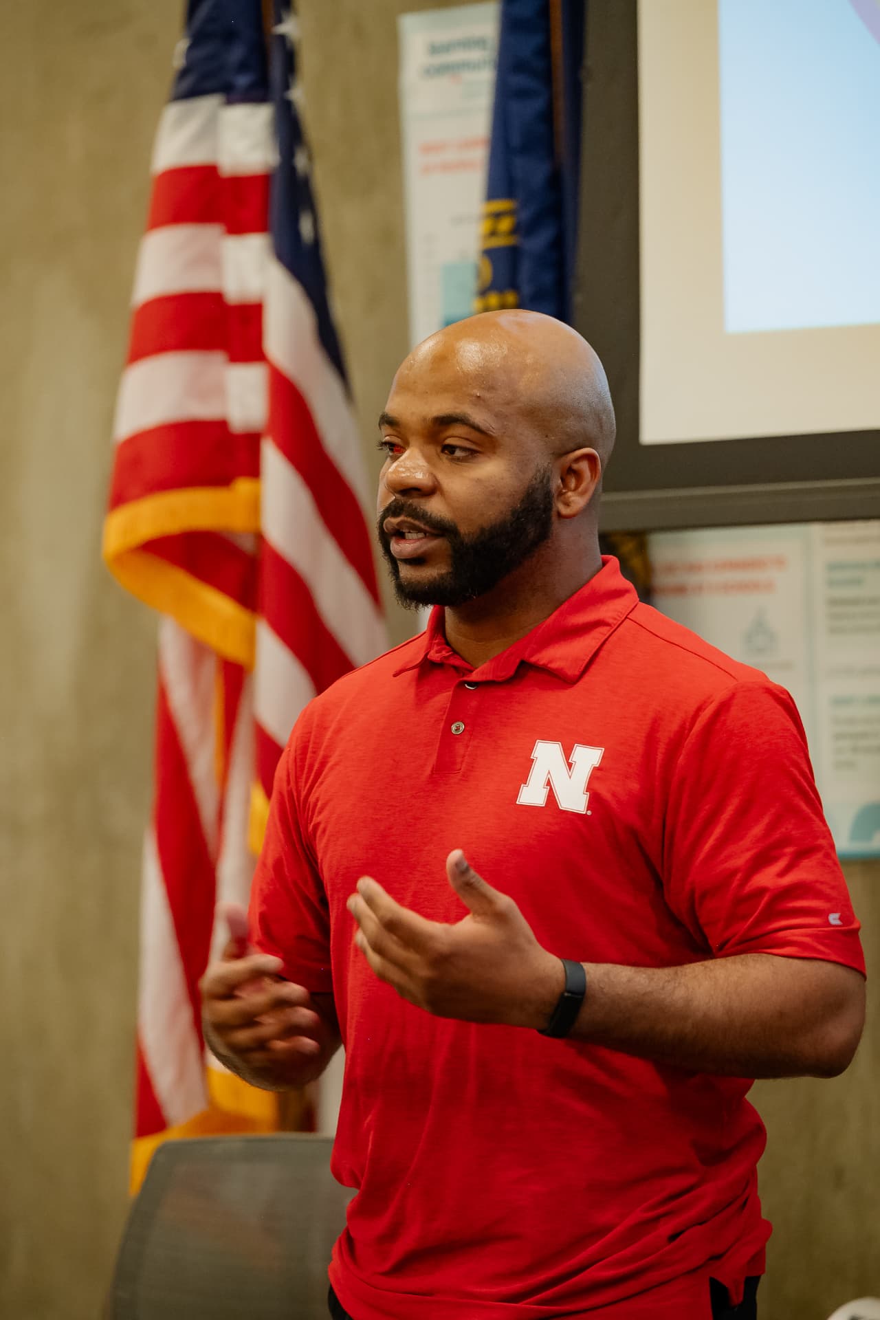 A presenter in a red shirt speaking to participants at the program